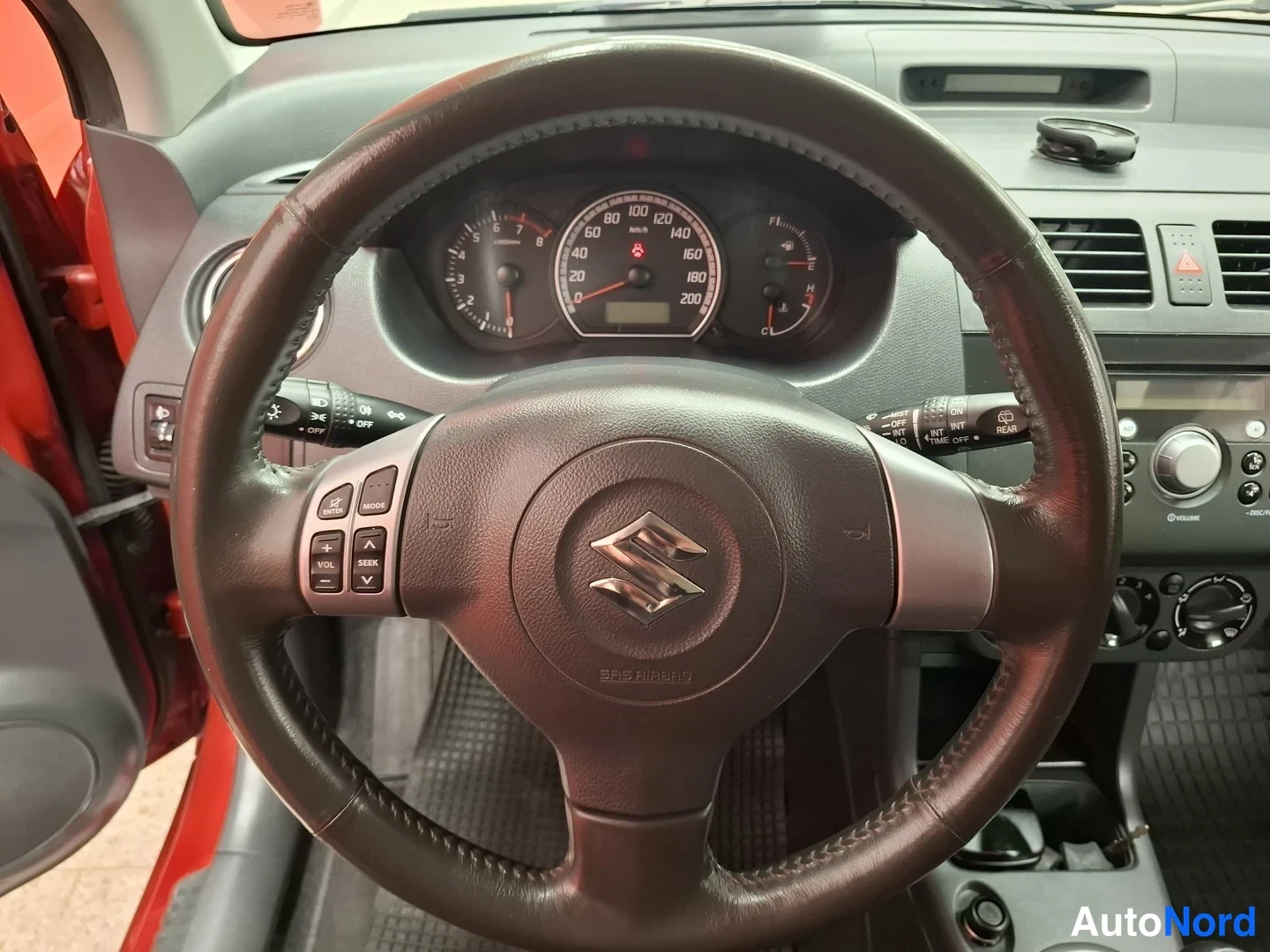 Etuviisto, nokka oikealle: Suzuki Swiftin ratti ja kojelauta lähikuvassa, mittaristo ja audio- ja valopyyhinsäädinokytkimet näkyvissä, ratissa SRS AIRBAG -teksti.
