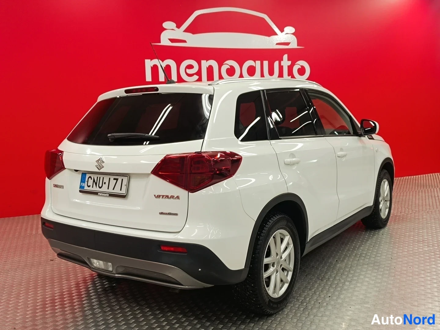 Takaviisto: Valkoinen Suzuki Vitara -maastauto takakulmasta vasemmalta, rekisterikilpi näkyvissä.