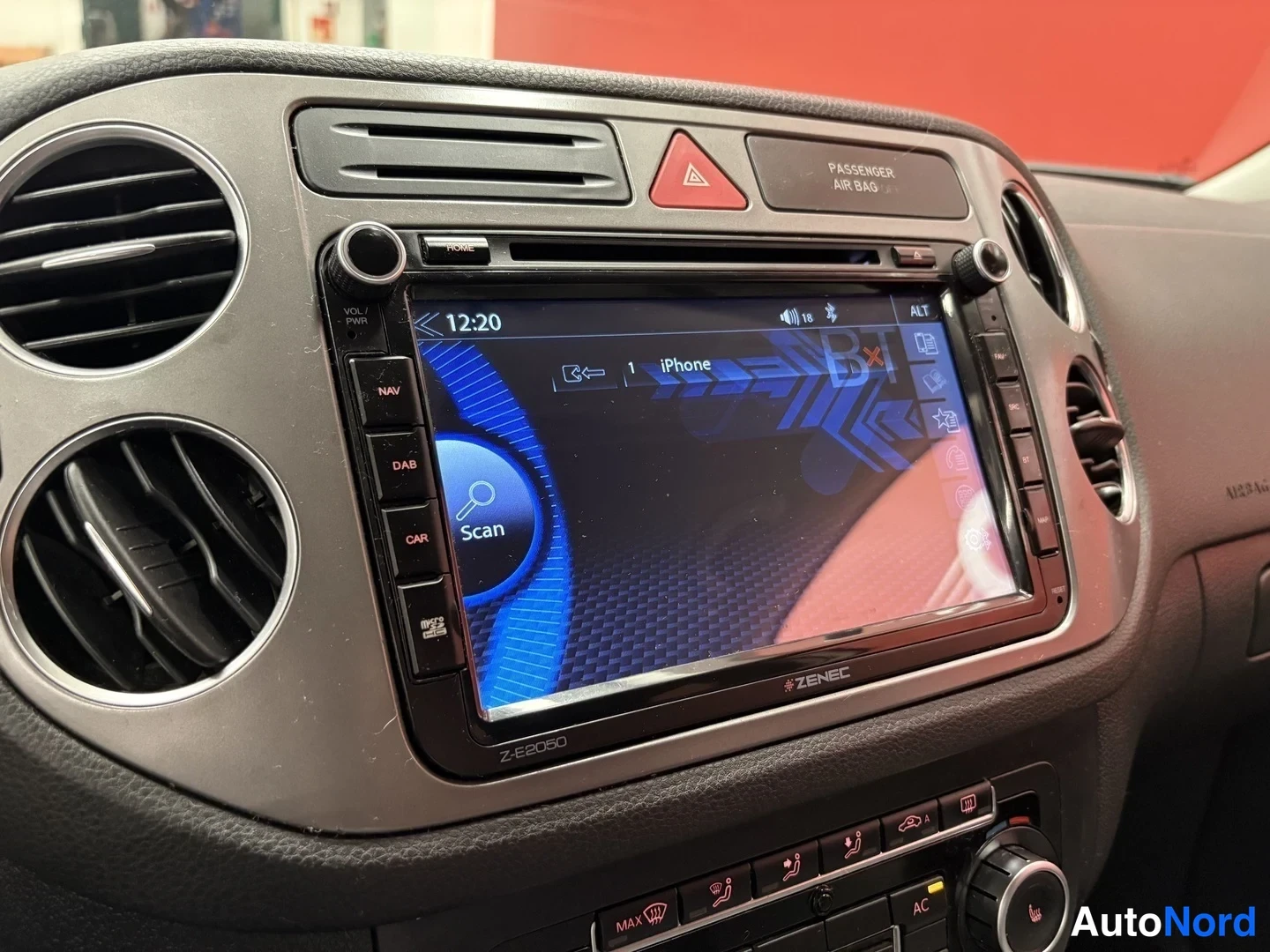 Yksityiskohta: Kojetaulun keskusyksikkö Zenec Z-E2060, jossa NAV-, DAB- ja CAR-napit, näytöllä iPhone-yhteys, alla AC- ja MAX-napit.