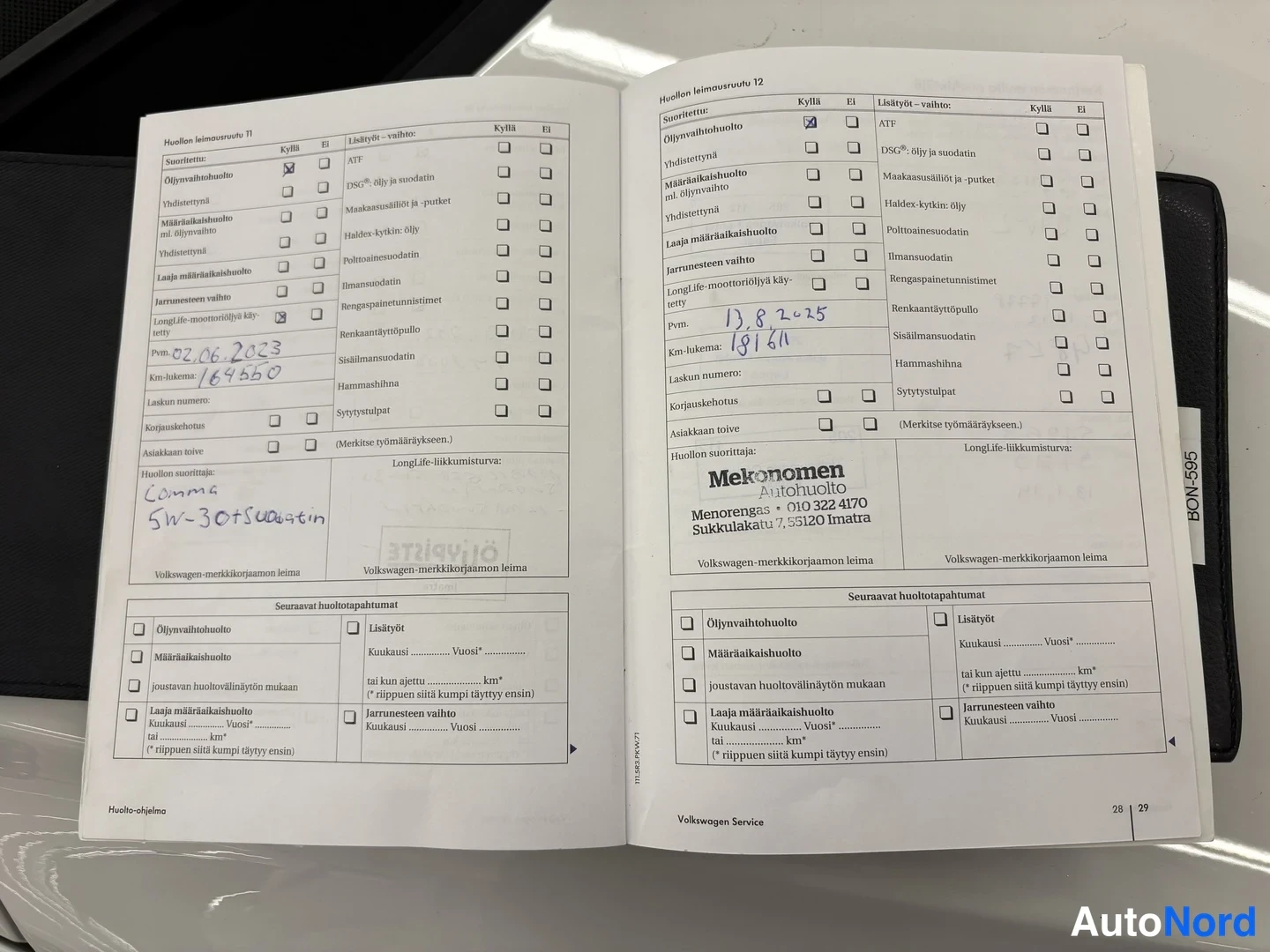 Muu: Avattu Volkswagen-huoltokirja, huoltolenomat sivut 28-29, merkinnöillä pvm 2.6.2023 (169550 km) ja pvm 13.8.2025 (181161 km), Menonomen Automoottorin leimalla.