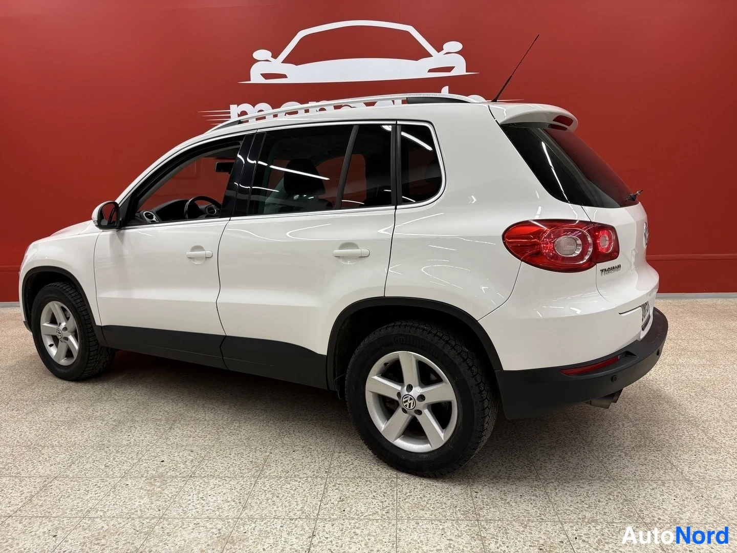 Takaviisto: Valkoinen Volkswagen Tiguan takakulmasta sisätiloissa, kylki ja perä näkyvät.