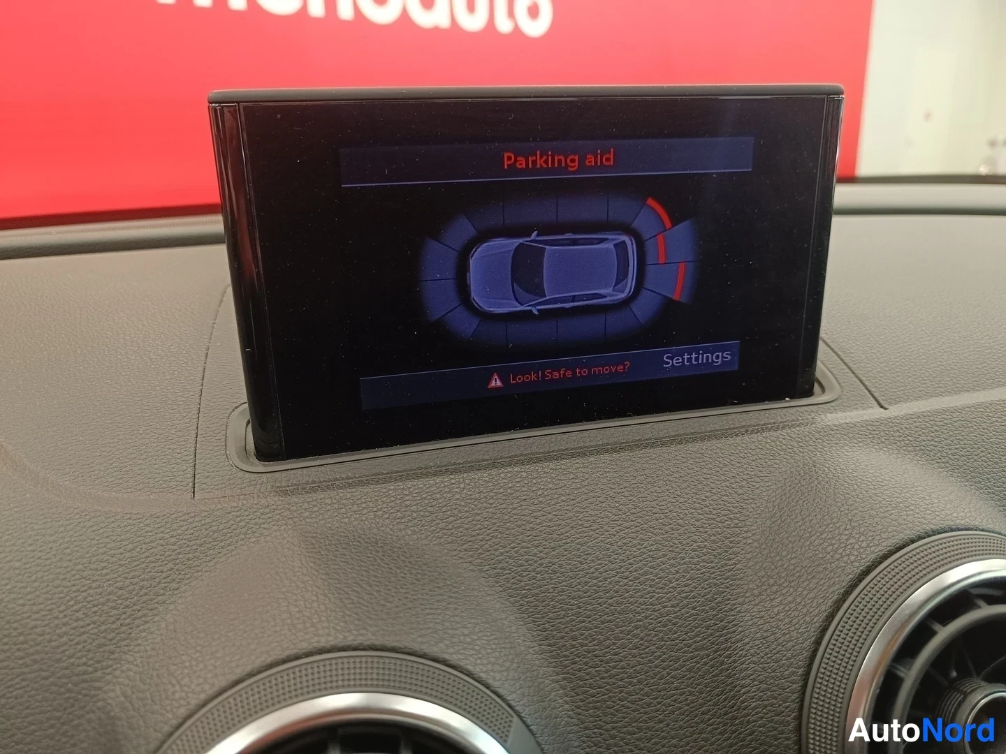 Muu: Näyttö keskitolalla näyttää 'Parking aid' -näkymän auton ympäristötutkalla; teksti 'Look! Safe to move?' ja 'Settings'.