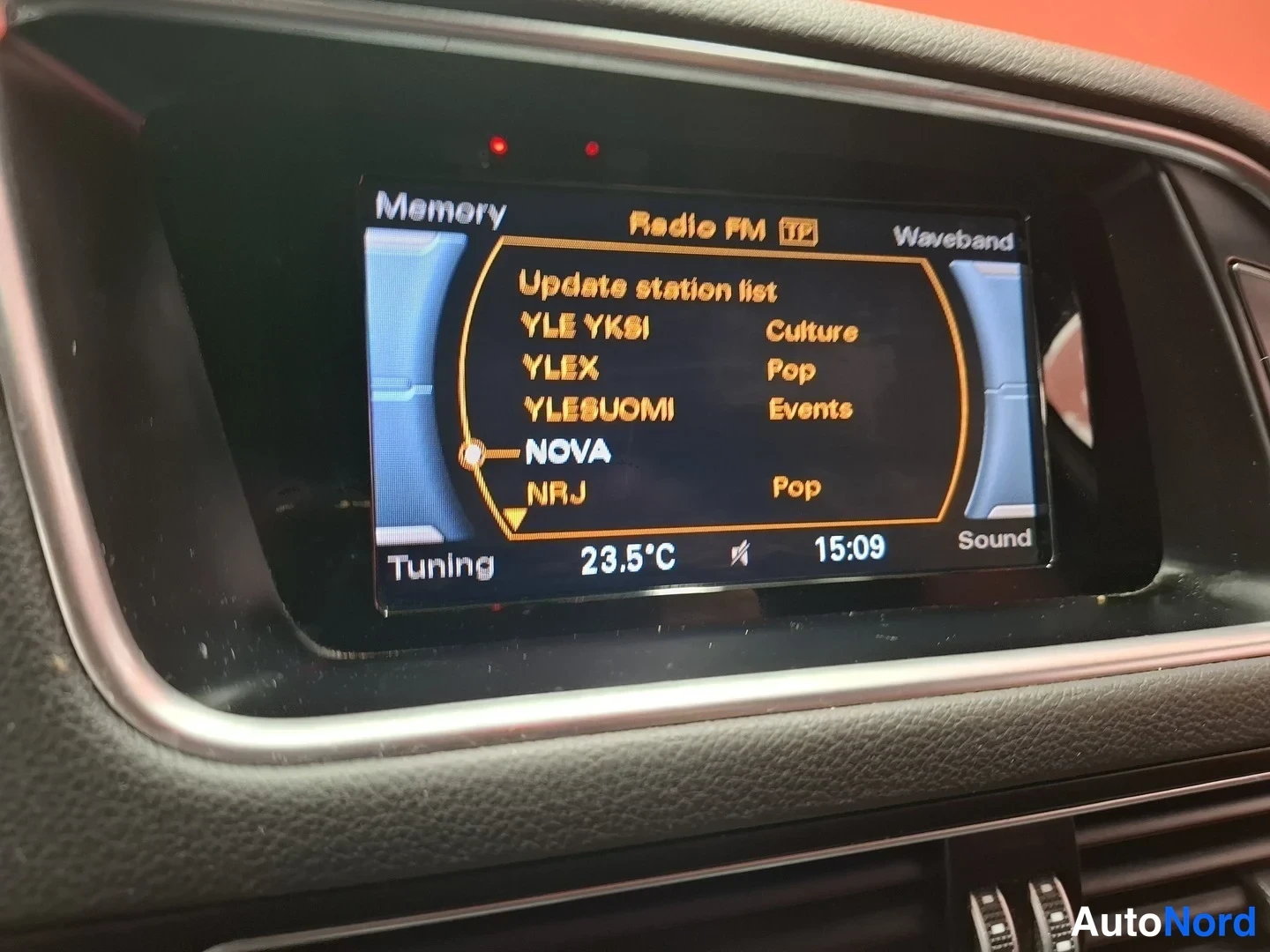 Muu: Auton kojelaudan näyttö, jossa radio FM -valikko kanavineen YLE YKSI, YLEX, YLESUOMI, NOVA ja NR.J; lämpötila 23,5 °C ja kellonaika 15:09.