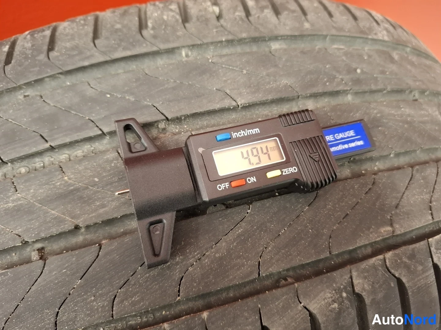 Yksityiskohta: Sähköinen urasyvyydenmittari renkaan pinnalla, näyttö lukee 4,94 mm.