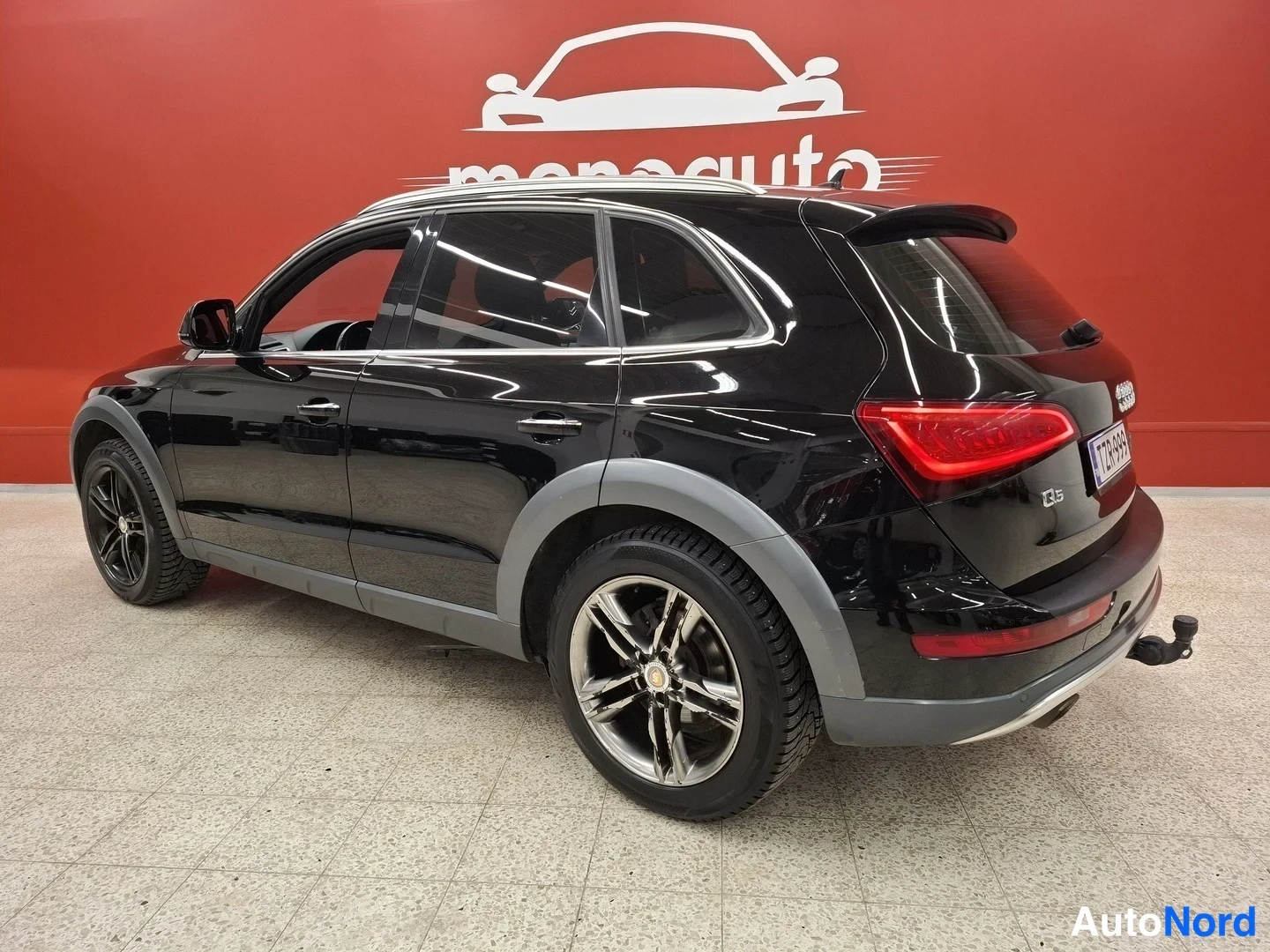Takaviisto: Mustan Audi Q5:n takakulma: takaosan äärivalot, takapuskuri ja hinaussilmukka näkyvät punaisen taustan edessä.
