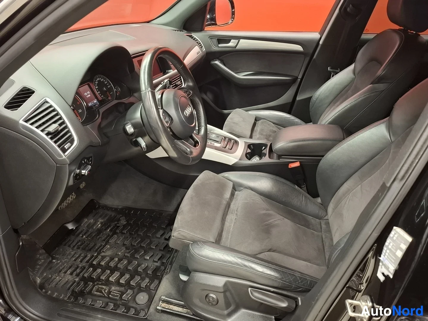 Muu: Audi Q5:n sisätilat: ohjauspyörä, kojelauta, etuistuimet ja matto, sisätilat ovat mustat.