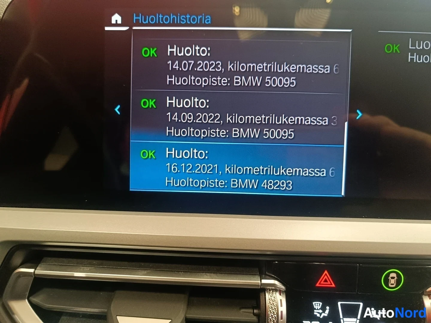 Yksityiskohta: Auton kojelaudan näyttö, jossa on Huoltohistoria-lista ja kolme huoltoa vuosilta 2021–2023.