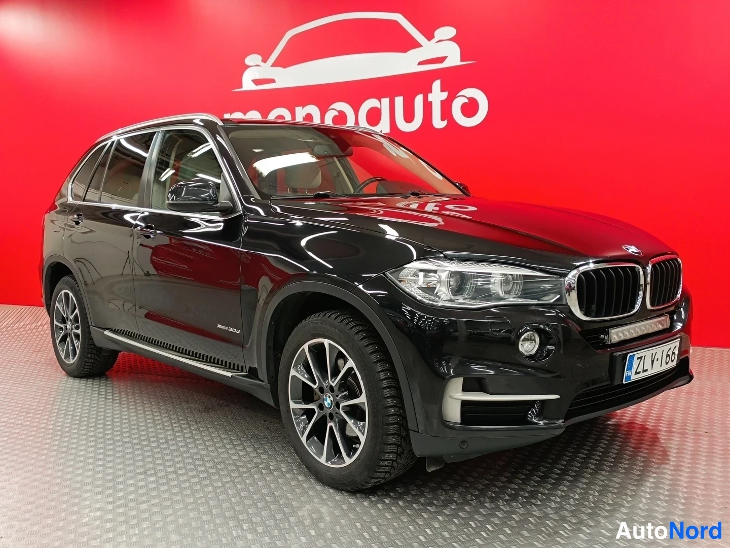 Etuviisto, nokka oikealle: Mustan BMW X5:n etukulmanäkymä, etupanoraama ja rekisterikilpi näkyvissä.