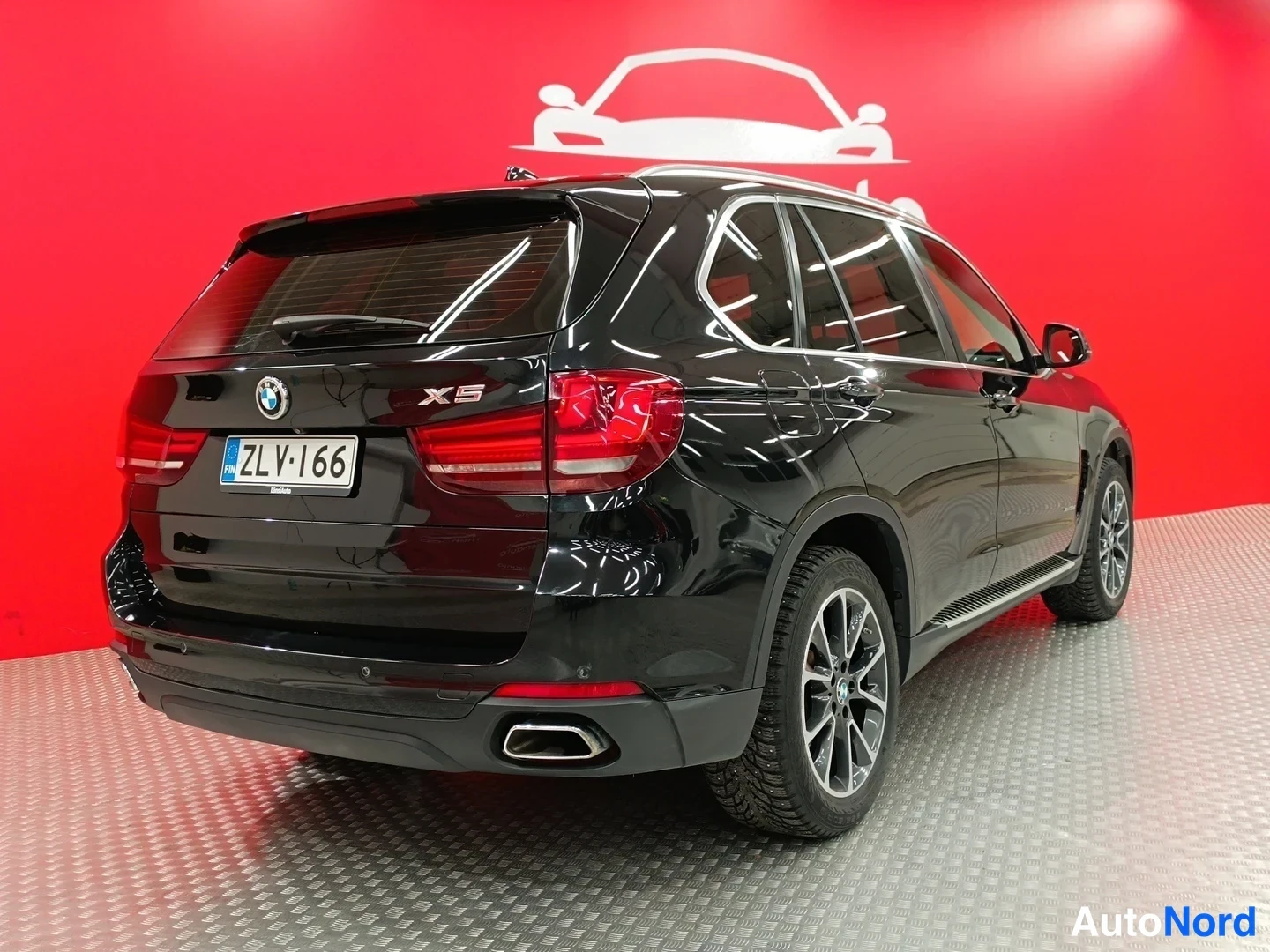 Takaviisto: Mustan BMW X5:n takakulmanäkymä, takamoottorin ja rekisterikilven näkyessä.