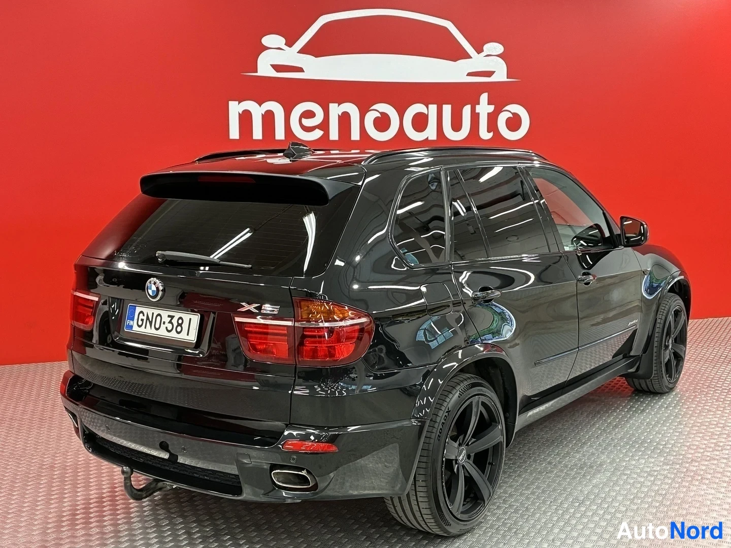 Takaviisto: Musta BMW X5 taka-35-kulmakuva oikealta, takavalot, X5-merkki ja rekisteritunnus näkyvissä, mustat kevytmetallivanteet.