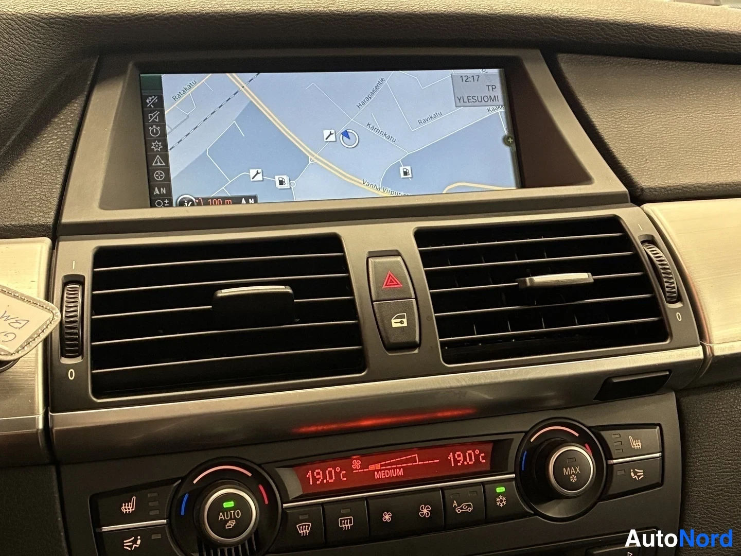 Yksityiskohta: Kojelaudan näyttö näyttää navigointikarttaa, alapuolella automaattiset ilmastointiasetukset 19,0 °C.