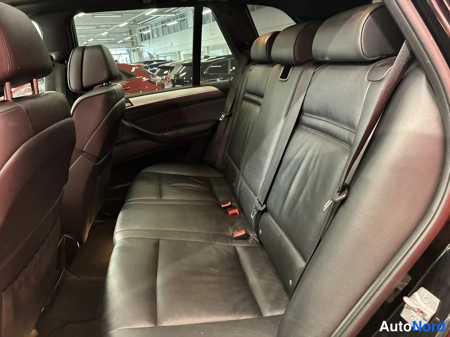 Muu: Auton takaistuin mustaa nahkaa, kolme istuinta ja takana katsotaan taaksepäin avatusta ovesta