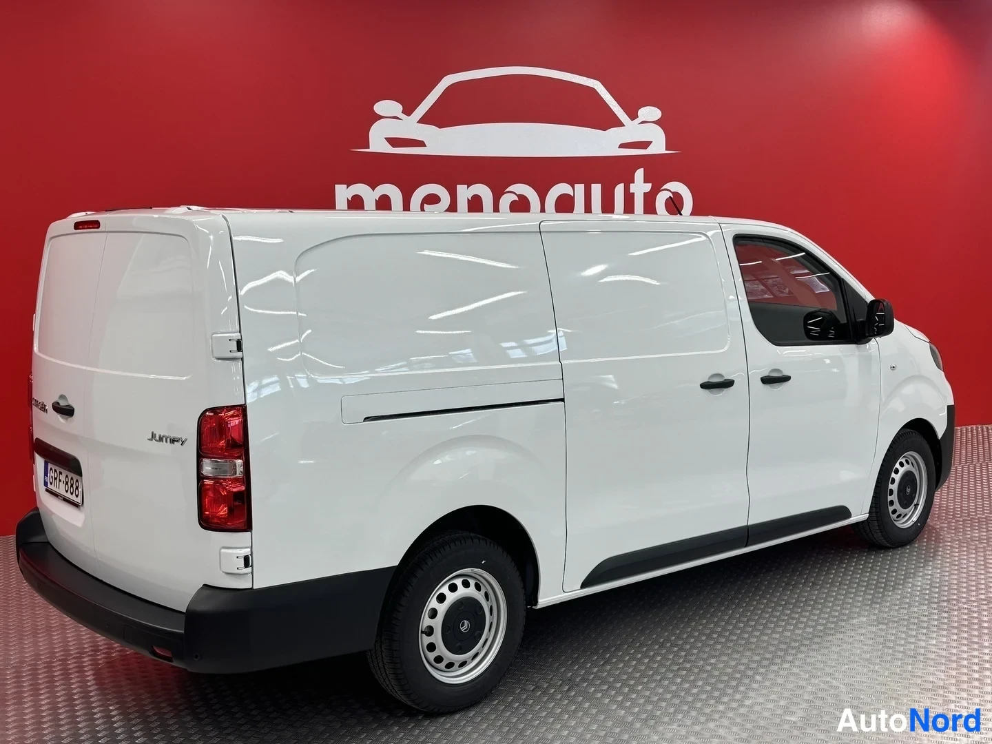 Takaviisto: Valkoinen Citroën Jumpy -pakettiauto takakulmassa, rekisterikilpi, punaisella Menoauton taustalla.