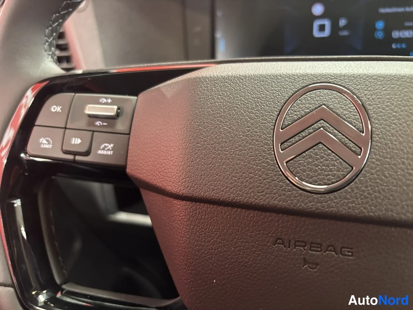 Muu: Ohjauspyörän vasen puoli lähikuvassa: Citroënin logo, AIRBAG-teksti ja nappiryhmä (OK, LIMIT, ASSIST).