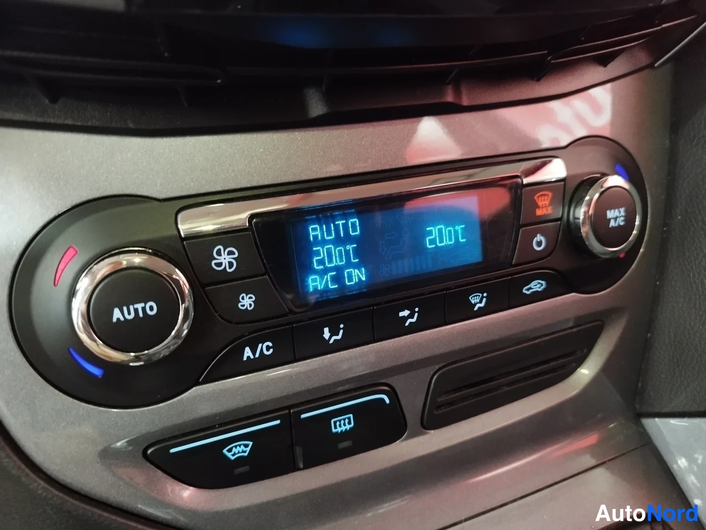 Yksityiskohta: Kaksivyöhykkeen automaattinen ilmastointi: näyttö lukee AUTO, 20°C ja A/C ON. Näkyvissä myös MAX A/C -nappi ja istuimenlämmityspainikkeet.
