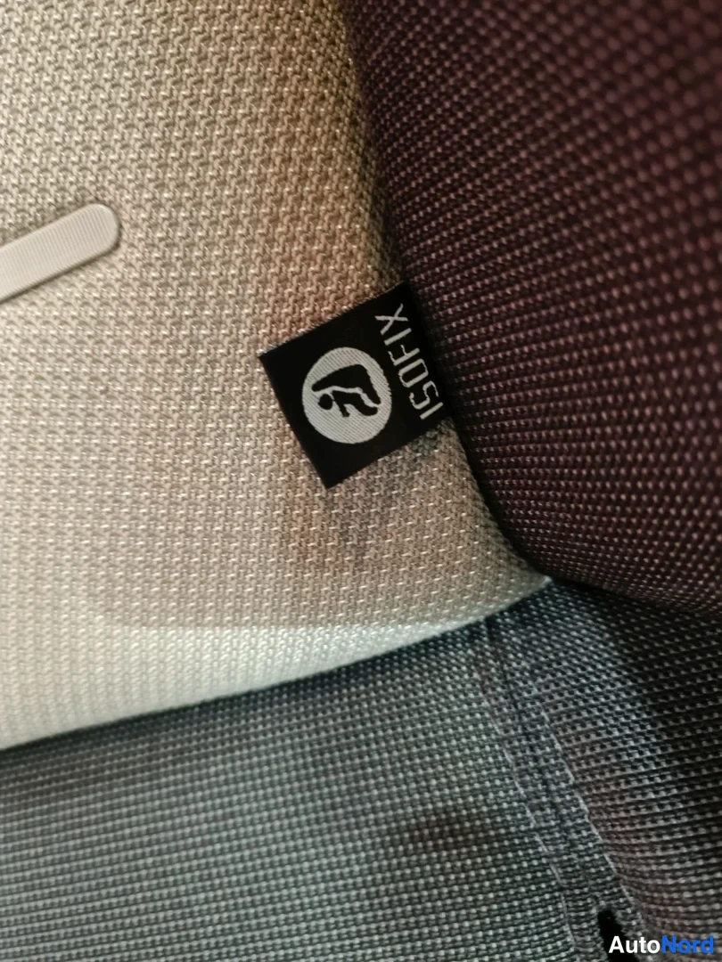 Yksityiskohta: Istuinten välissä musta ISOFIX-tunnuslappu