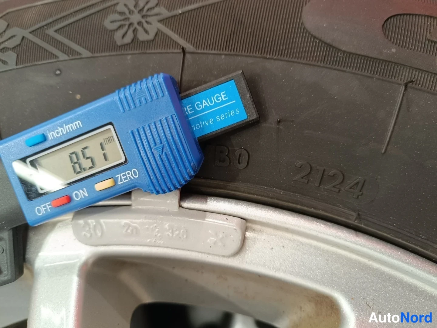 Yksityiskohta: Renkaan urasyvyysmittari näyttää 8,51 mm auton renkaan kulutuspinnalla.