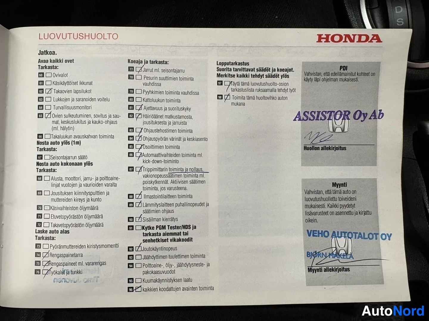 Yksityiskohta: Avattu Honda-luovutushuoltolomake, jossa on ruksattuja tarkastuskohtia ja allekirjoituksia.