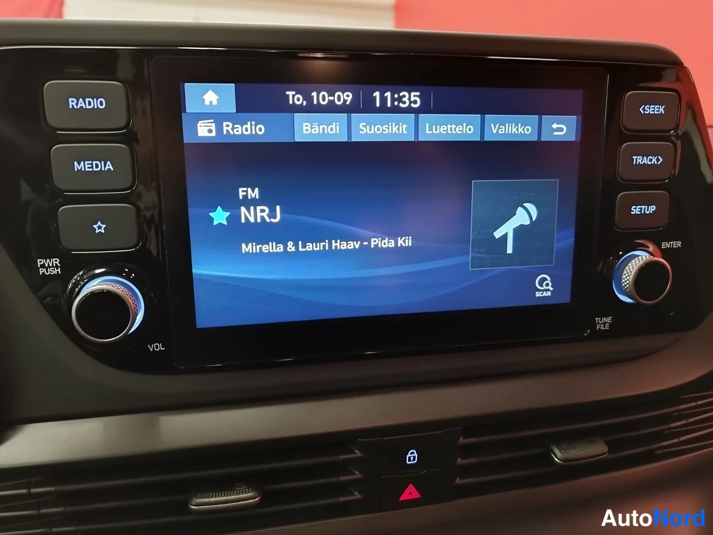 Edestä: Radiota näyttävä infotainment-näyttö: FM NRJ, kappale 'Mirella & Lauri Haav - Pida Kii', kellonaika 11:35; ympärillä RADIO-, MEDIA-, SETUP- ja äänenvoimakkuusnu