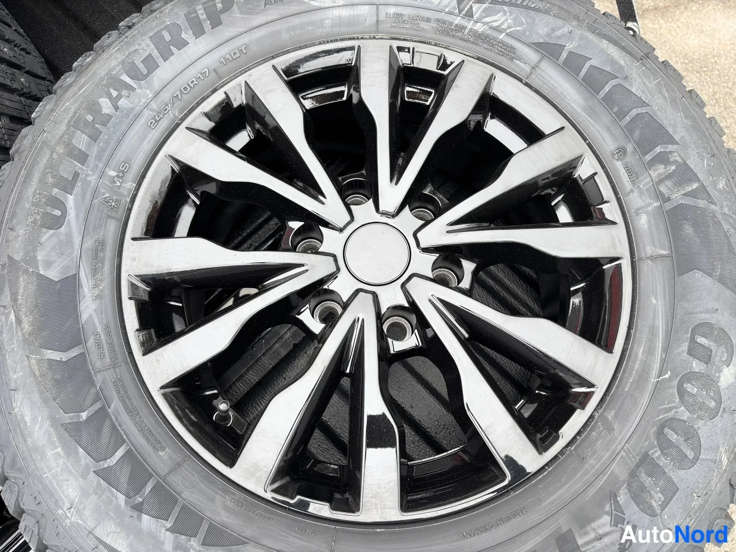 Yksityiskohta: Musta-valkoinen monipuolainen kevytmetallivanne, Goodyear UltrGrip -rengas 245/70 R17 110T M+S.