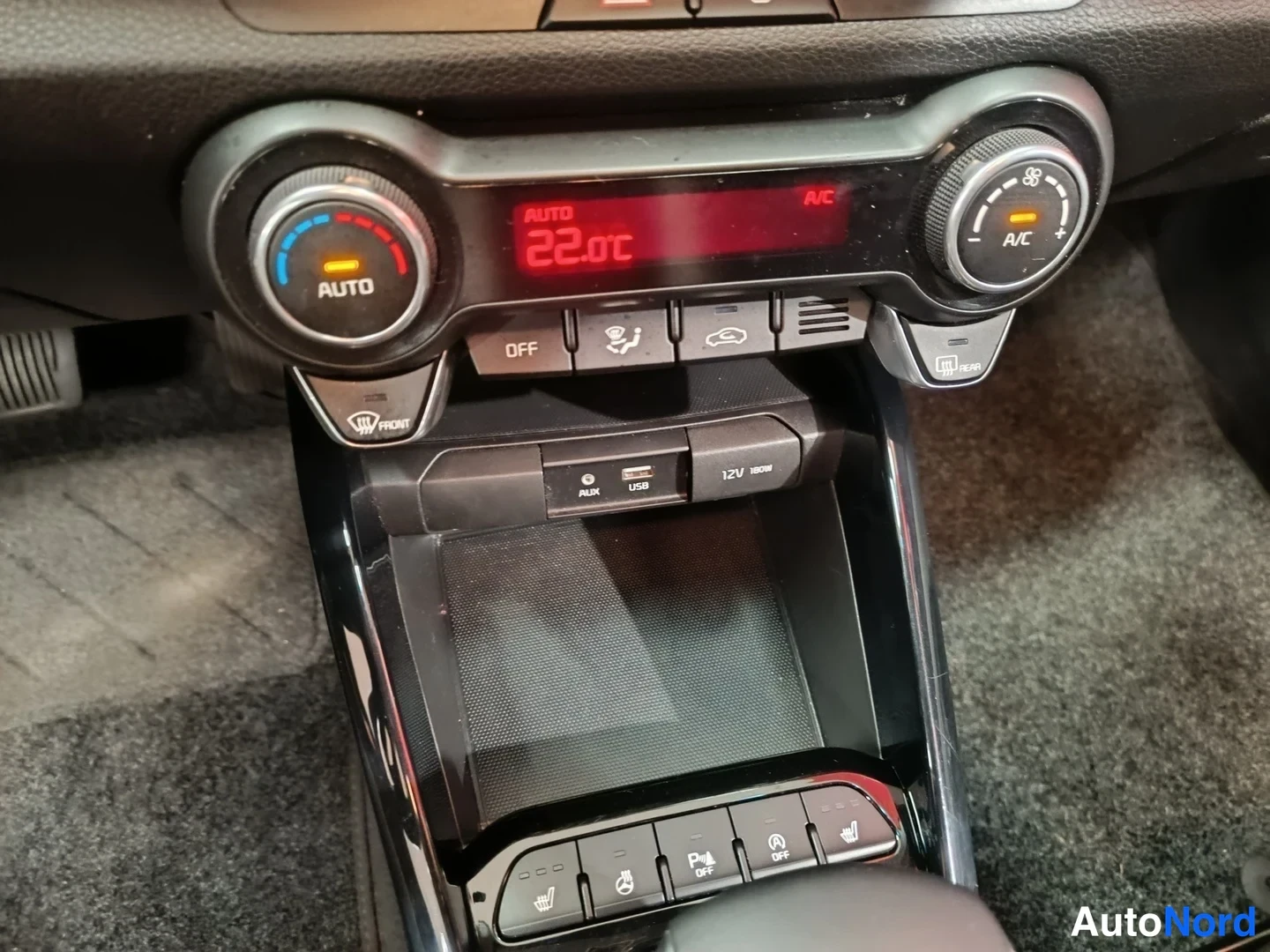 Muu: Ilmastointipaneeli keskellä näyttää 22.0°C:ta; AUTO AC, A/C, OFF- ja icetä-painikkeet ovat ympäröivät paneelia; AUX-, USB- ja 12V 150W-pistorasia on alapuolella