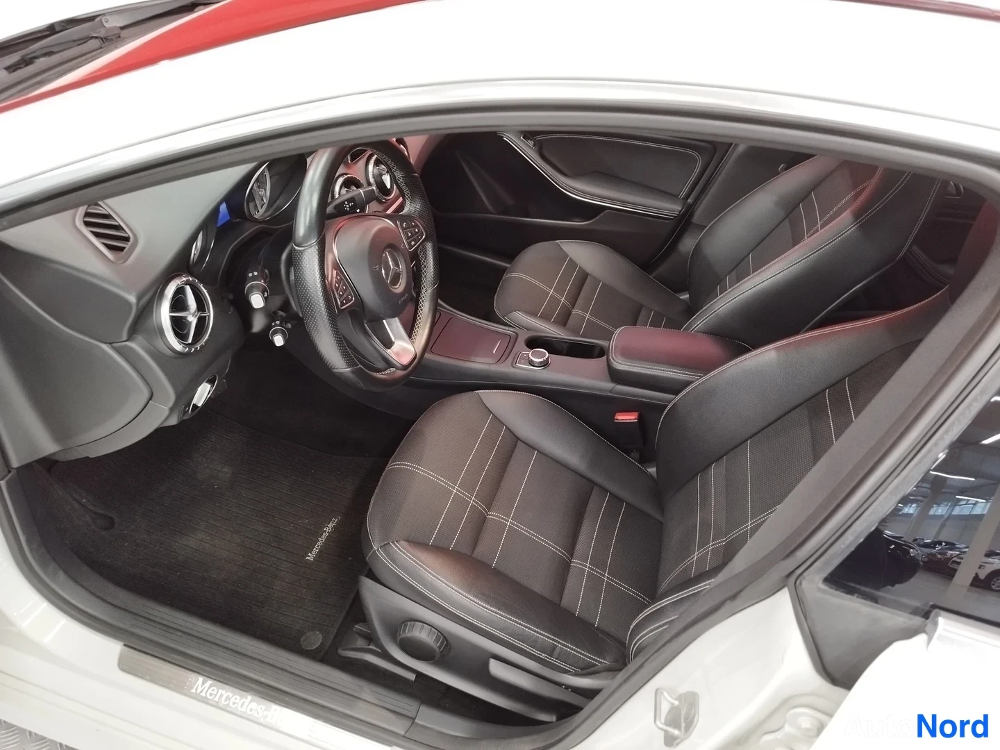 Muu: Mercedes-Benzin etumatkustamotilaa: mustat istuimet valokuituompeleilla, Mercedes-merkkinen ohjauspyörä ja ovikynnys, matto Mercedes-Benz-logolla.