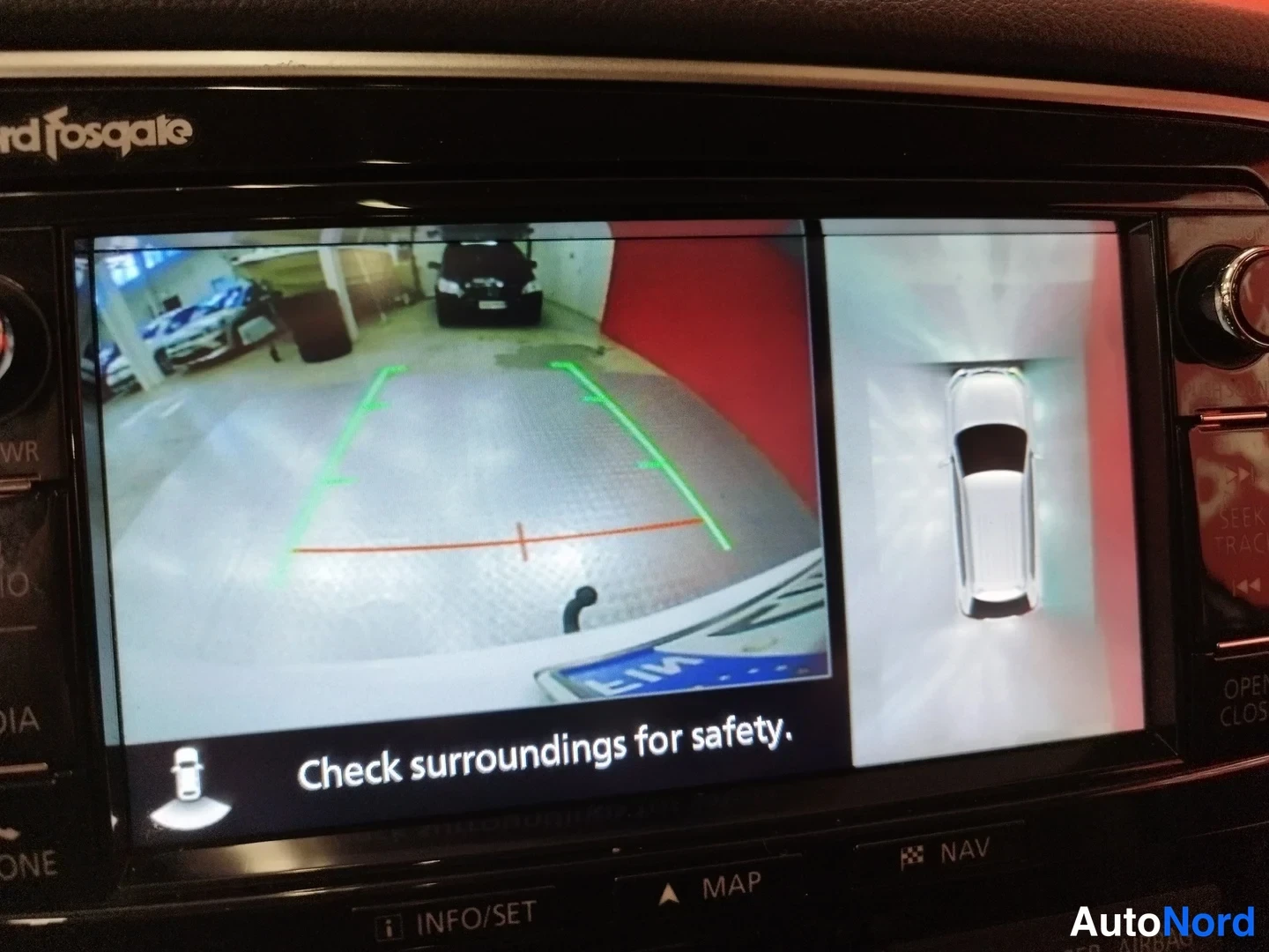 Muu: Peruutuskameran kuva näytöllä vihreine ohjausviivoineen; teksti 'Check surroundings for safety.', vasemmalla autotalli ja oikealla auton ympärivarian kartta.
