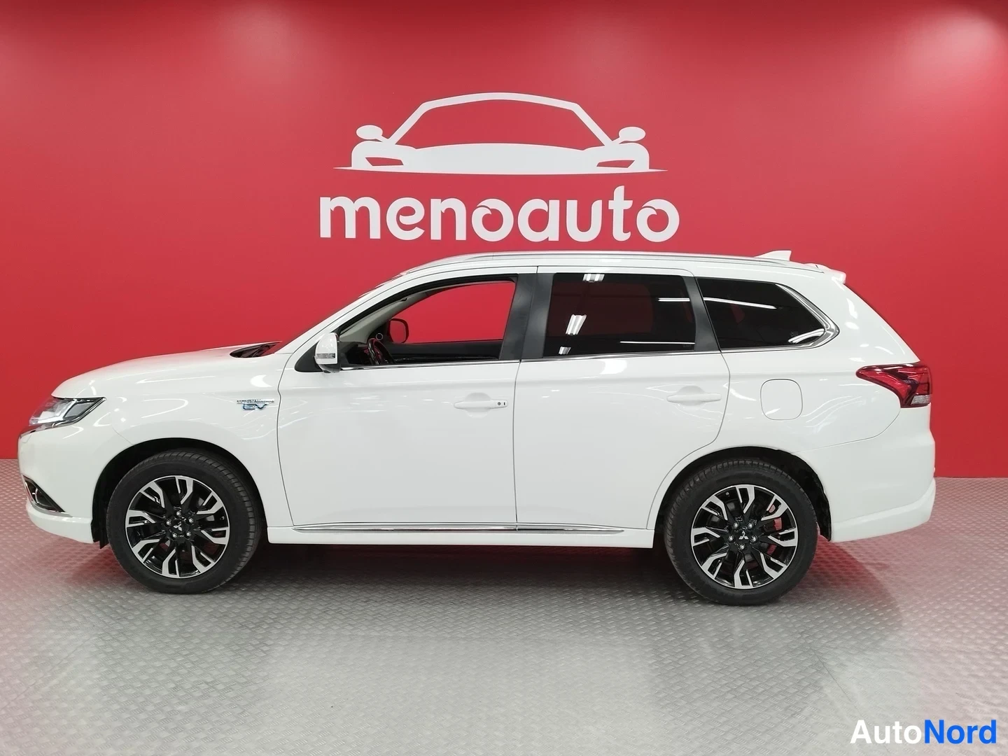 Etuviisto, nokka vasemmalle: Valkoisen Mitsubishi Outlanderin kylkinäkymä, keula vasemmalla, mustat kevytmetallivanteet ja punainen menoauto-taustaseinä.