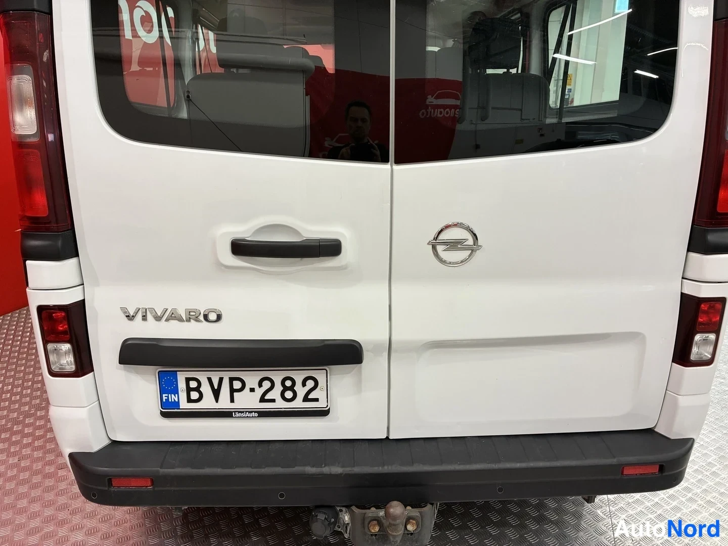 Takaa: Valkoisen pakettiauton takaosa: kaksoistakaluukut, Opel-merkki ja VIVARO-teksti, rekisterikilpi, punaiset takavalot ja hinauskytkin alatasossa.