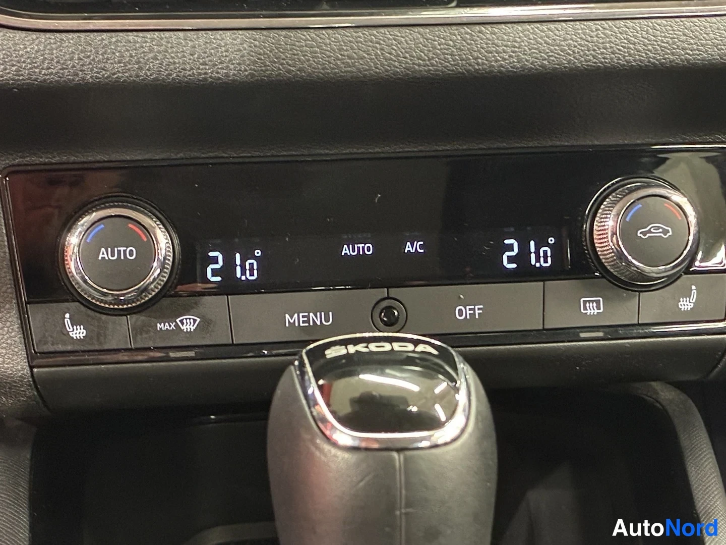 Muu: Kaksivyöhykeilmastointipaneeli näytöillä 21.0° molemmin puolin, AUTO ja A/C -painikkeet; allas Škoda-merkitty vaihteenvalitsimen nuppi.