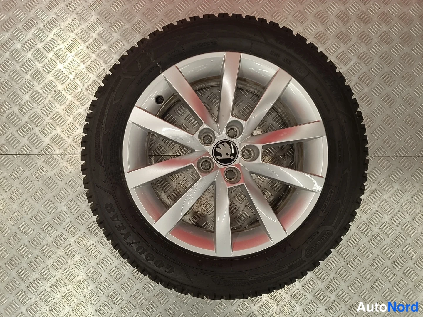 Muu: Irrotettu alumiinvanne rengas Goodyear-nastarenkaalla, Skoda-täplä vanteessa, näytetty pitsahtieltä kuvattuna.