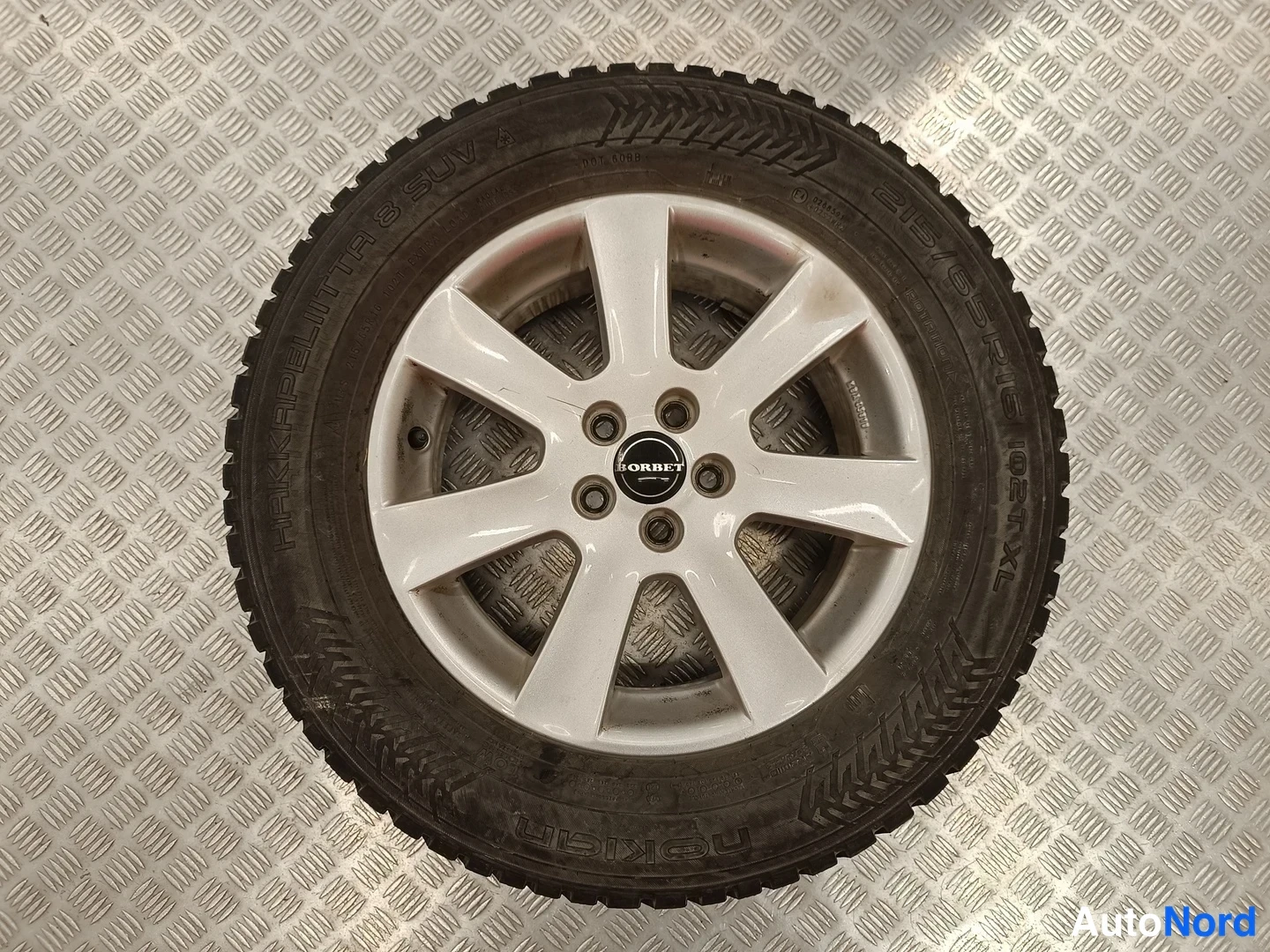 Yksityiskohta: Nokian Hakkapeliitta 8 SUV -talvirengas 215/65 R16 valkoisella viisikuvioisella alumiinivanteella porrastetulla lattialla.