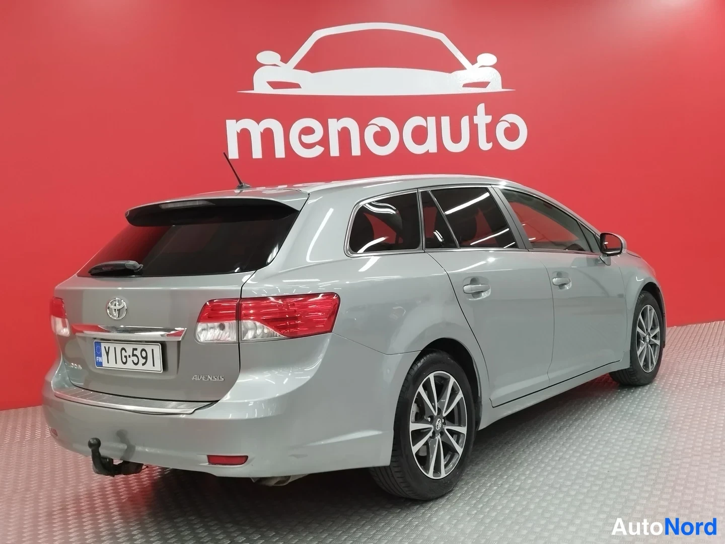 Takaviisto: Hopeanharmaan Toyota Avensis -farmarin takakulma, perä ja rekisterikilpi näkyvissä.
