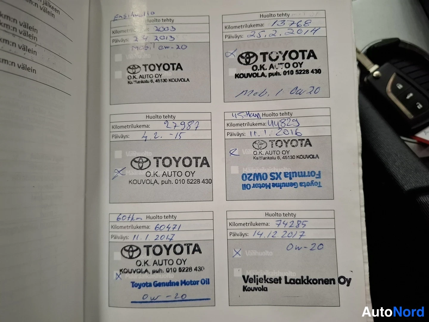 Yksityiskohta: Huoltokirjan sivu, jossa kuusi täytettyä 'Huolto tehty' -kenttää Toyota O.K. Auto Oy:n leimoilla ja käsin kirjoituilla kilometrilukemilla.