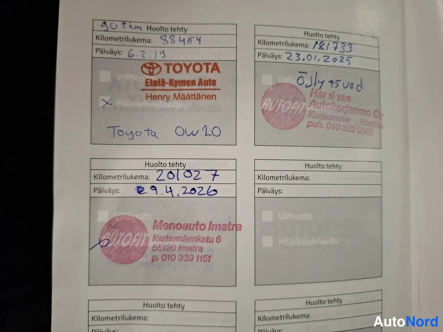 Yksityiskohta: Huoltokirjan sivu, jossa uusia huoltoyhtiöiden leimoja: Etelä-Kymen Auto, Autofit Harjian Autokorjaamo Oy ja Menoauto Imatra.
