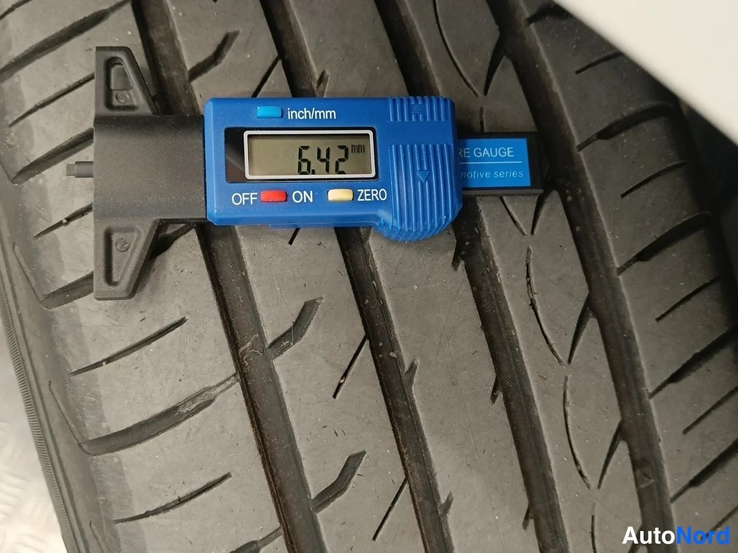 Yksityiskohta: Renkaan urasyvyyden mittaus: digitaalinen mittari näyttää 6,42 mm.
