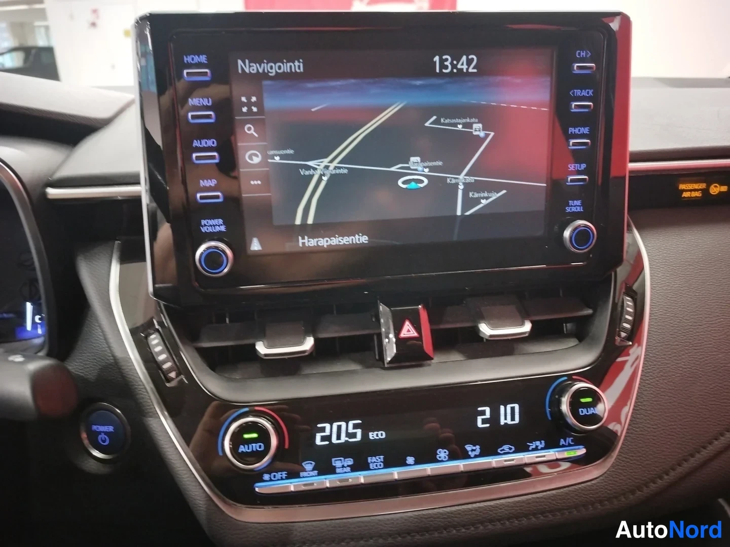 Edestä: Keskikonsolin infotainment-näyttö, jossa on navigointi käynnissä, sekä alla automaattinen kaksivyöhykeilmastointi (AUTO/DUAL) ja ECO-tilan näyttö.