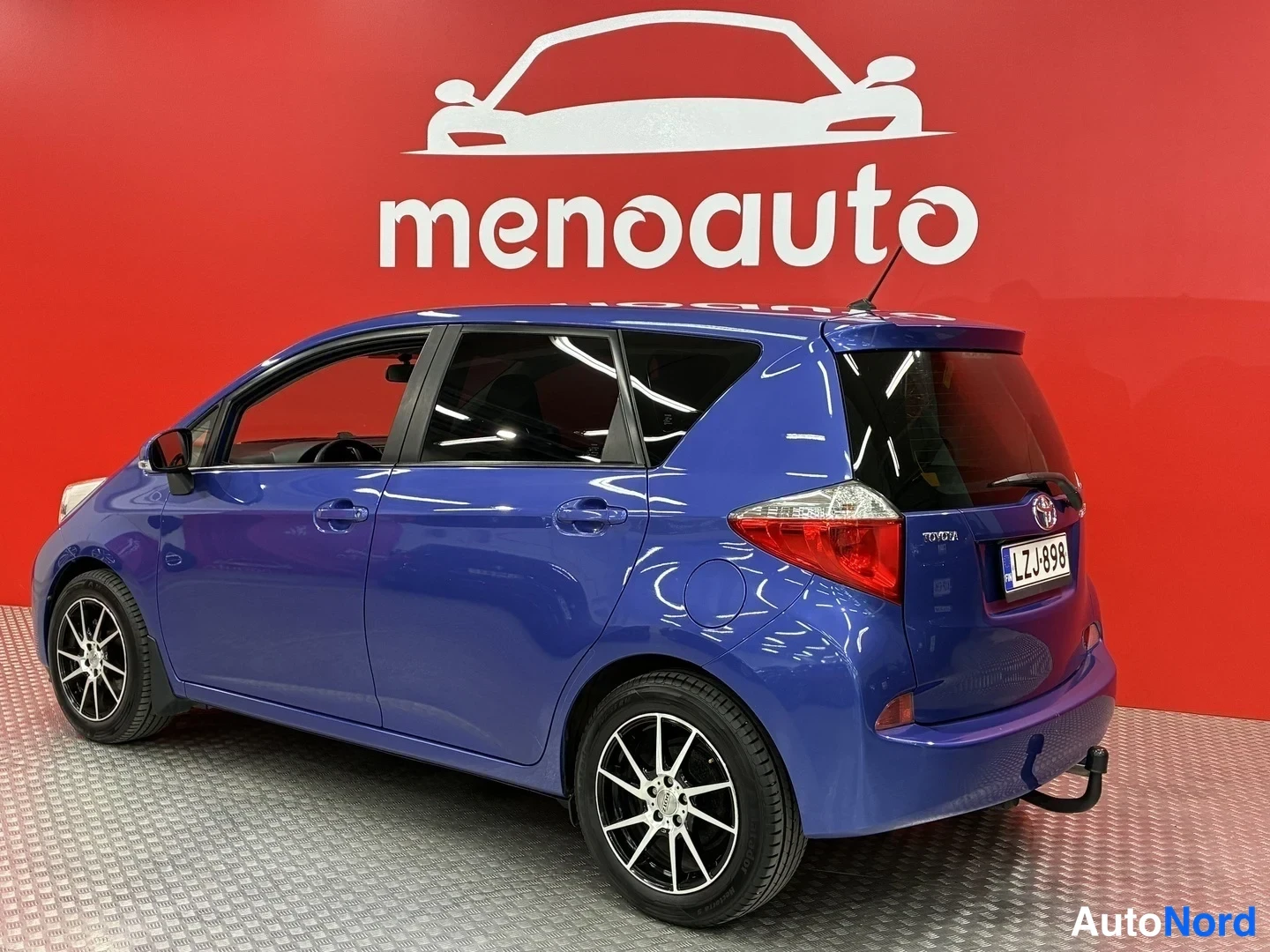 Takaviisto: Sinisen Toyota Verso-S:n takakolmannesosa, rekisteritunnus, pakokoukku näkyvissä.