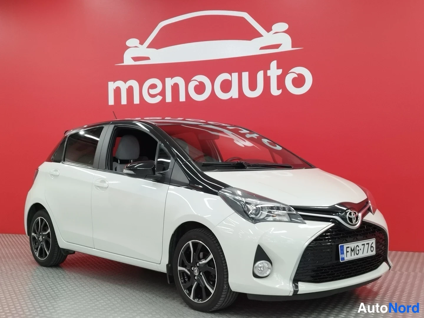 Etuviisto, nokka oikealle: Valkoinen Toyota Yaris viistoperä, etukulmanurikka oikealta, musta katto ja hohlennetut alumiinivanteet, rekisteritunnus.