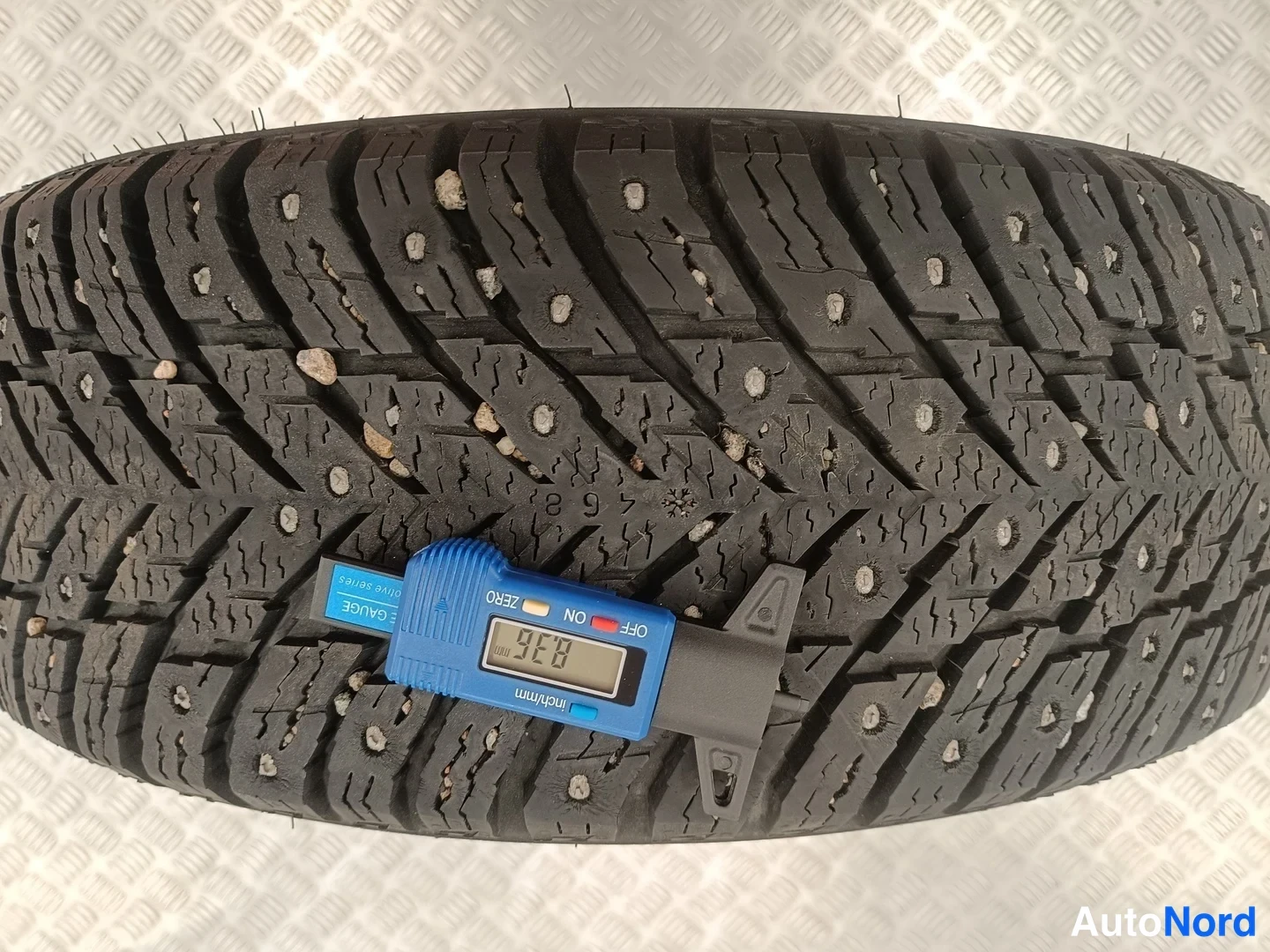 Yksityiskohta: Talvirenkaan kulkuupinta nastoilla, mittari näyttää 8,36 mm.