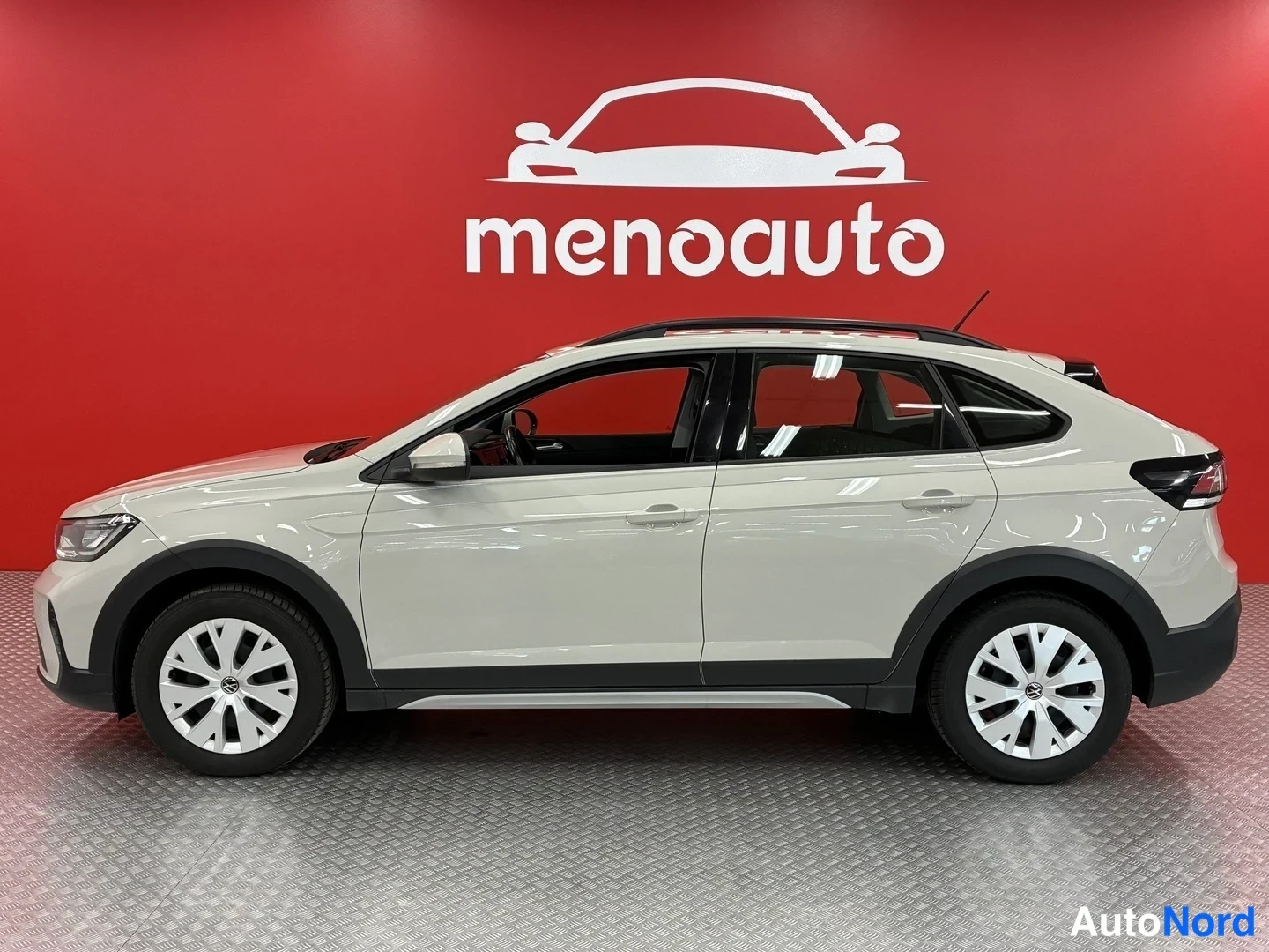 Etuviisto, nokka vasemmalle: Valkoisen Volkswagen Taigo -henkilöauton sivukulmanäyttö, kylki ja keulan etupaneli näkyvissä punaisella menoauto-taustalla.