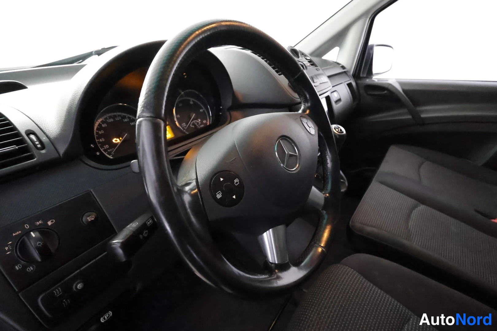 Yksityiskohta: Ohjaamo näkymä Mercedes-tähtimerkillä varustetusta monitoimiohjauspyörästä ja mittaristosta.