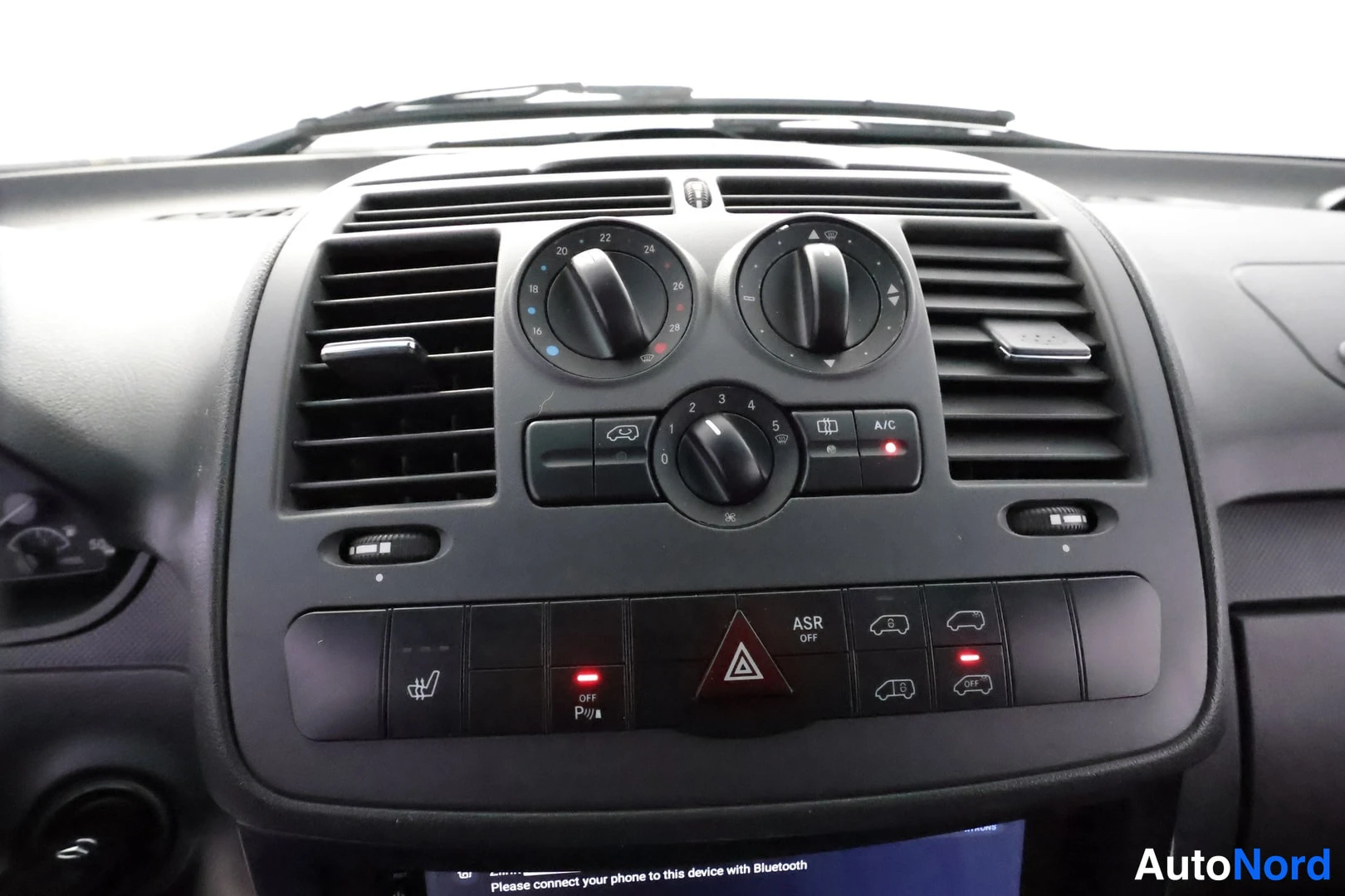 Muu: Kojelaudan keskikonsolin väljäys: kierrätysilmastointinupit, A/C-painike, ASR OFF -painike, varoitusvilkkupainike ja Bluetooth-kehote näytöllä.