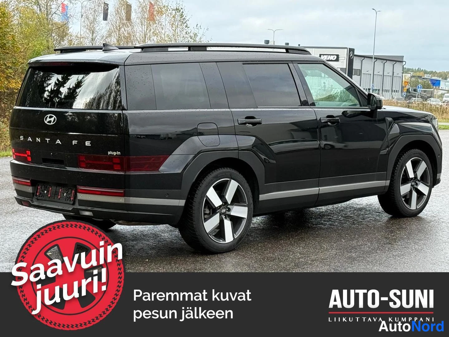 Takaviisto: Mustan maastoauton takakulmaku oikealta; kylki ja takaosa näkyvissä, boot-lidilla SANTA FE- ja plug.in -tekstit.