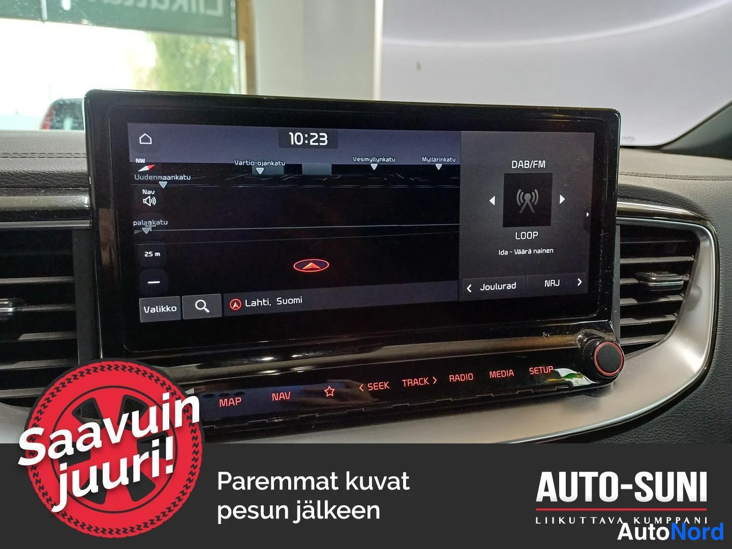 Muu: Kojetason infotainment-näyttö, jossa navigointikartta ja DAB/FM-radio kanavalla LOOP – Ida – Väärä nainen, auton sisätiloissa.