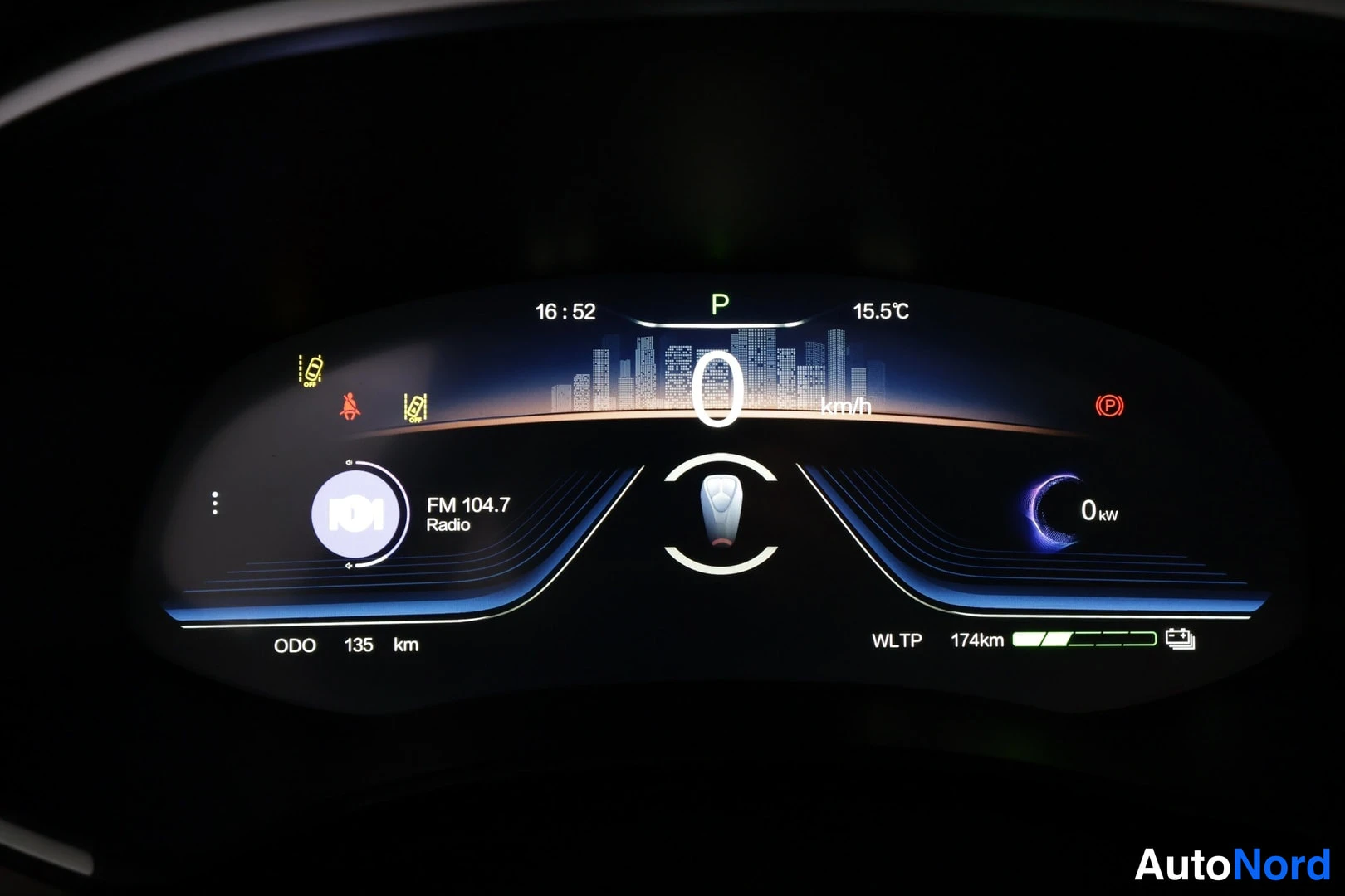 Muu: Digitaalinen mittaristö pimeässä: nopeus 0 km/h, vaihde P, ODO 135 km, WLTP 174 km, FM 104.7 Radio.