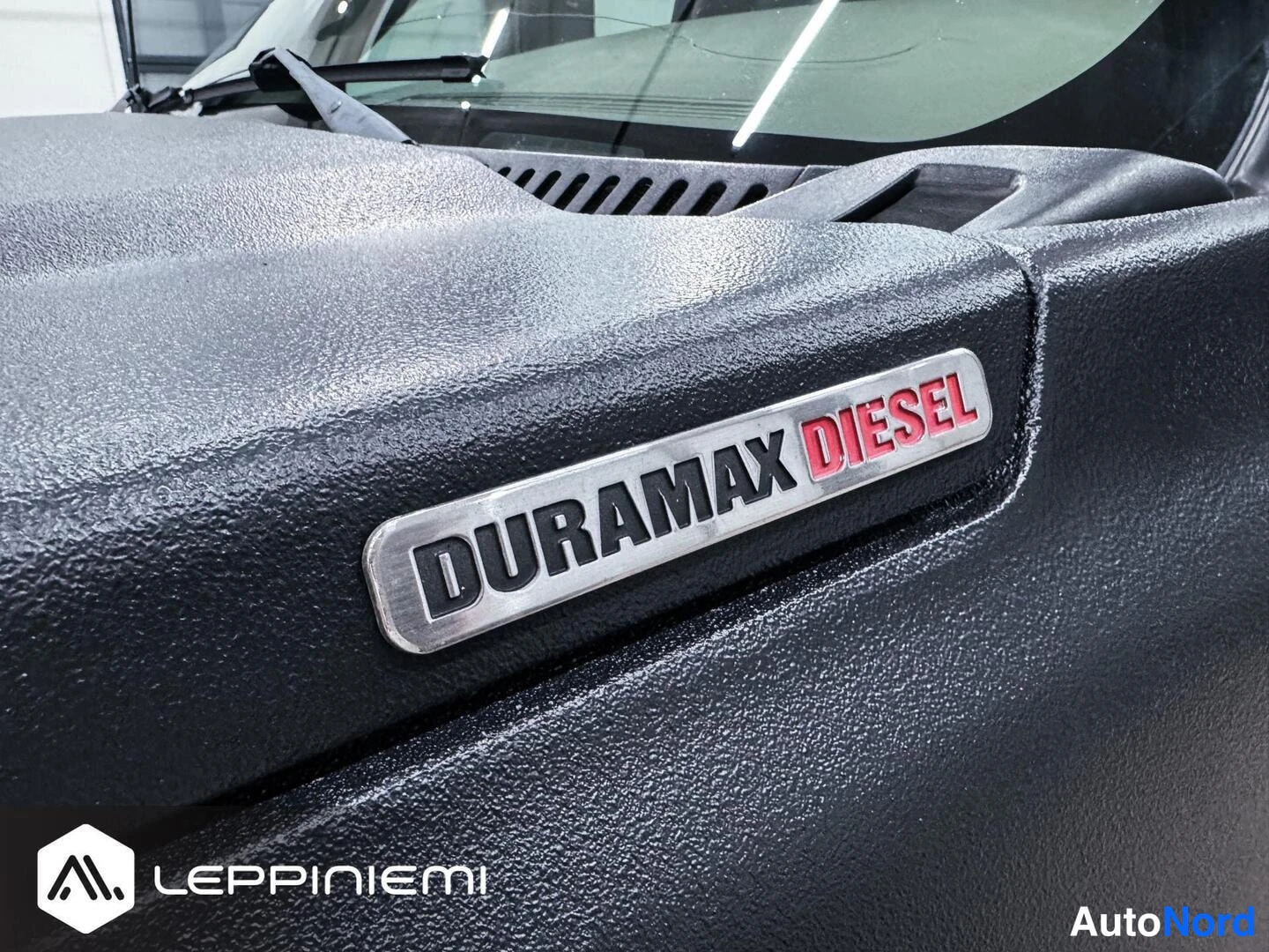 Muu: Sulku kuva mustaan konepeltiin paikalletetusta DURAMAX DIESEL-merkistä, taustalla näkyy lasissa kilpi.
