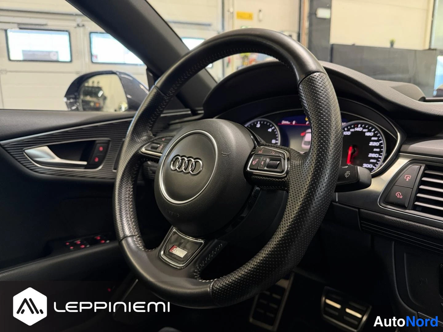 Yksityiskohta: Audi-ohjauspyörä multi-toiminnollisilla näppäimillä, mittaristo ja polkimet näkyvät sisätiloissa.