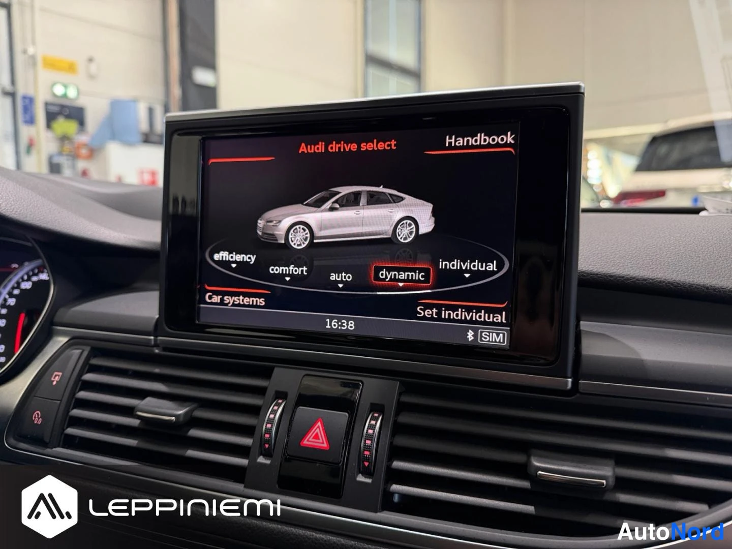 Yksityiskohta: MMI-näyttö näyttää Audi drive select -valikon (efficiency, comfort, auto, dynamic, individual), dynamic korostettuna, kello 16:38.