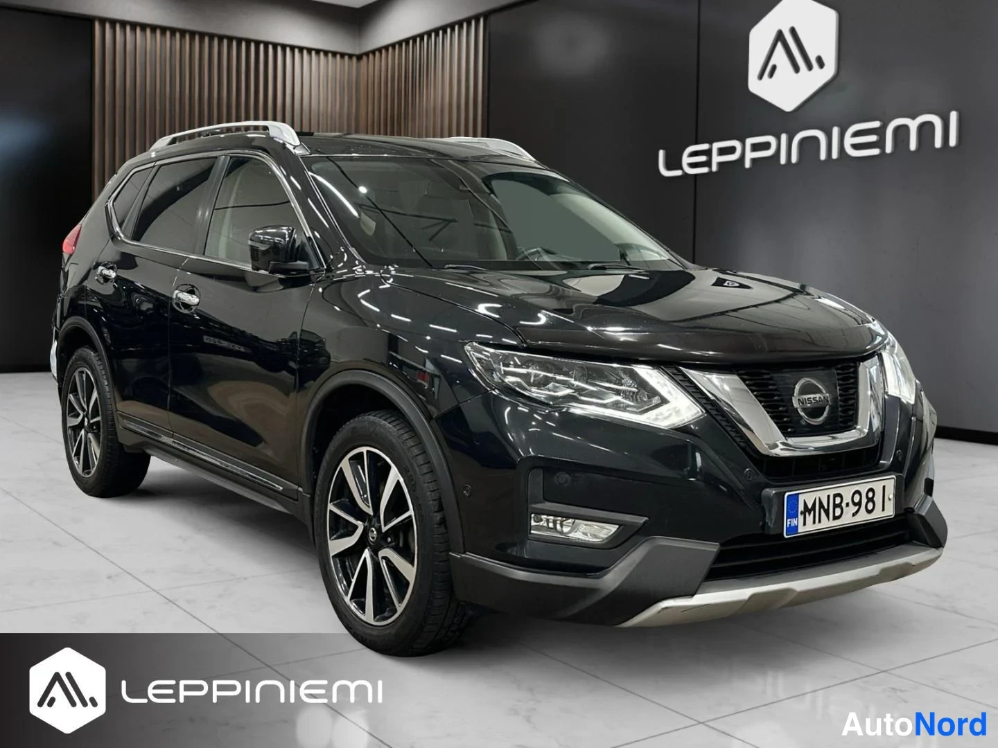 Etuviisto, nokka oikealle: Musta Nissan X-Trail etuviistosta oikealta etukulmasta, rekisteritunnus.